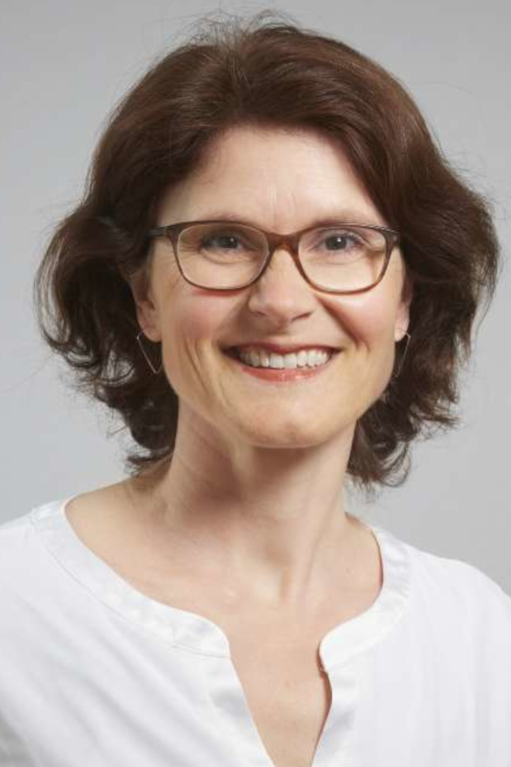 Porträt einer lächelnden Frau mit Brille.